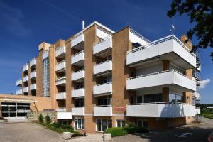 een bakstenen gebouw met witte balkons op een parkeerplaats bij Haus Frauenpreiss F502 in Cuxhaven
