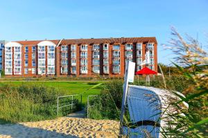 um grande edifício com um campo de voleibol em frente em Haus Horizont H513 em Cuxhaven