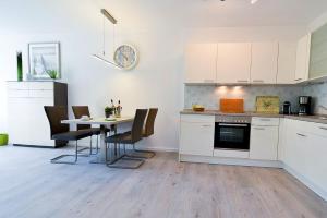 una cocina con armarios blancos y una mesa con sillas. en Haus Frauenpreiss F504, en Cuxhaven