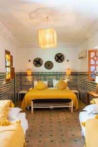 1 Schlafzimmer mit 2 Betten und gelber Bettwäsche in der Unterkunft Riad Le Marocain in Marrakesch