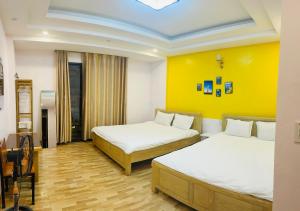 Habitación con 2 camas y pared amarilla. en My Dream Hotel, en Sa Pa