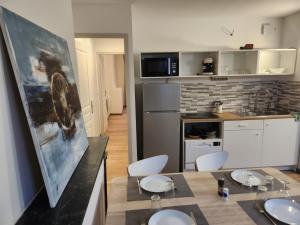 Agréable appartement, lumineux في بار لو دوك: مطبخ مع طاولة وكراسي و لوحة