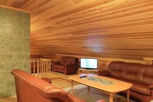 ein Wohnzimmer mit Ledersofas und einem TV in der Unterkunft Aapishovi Chalet in Tapio