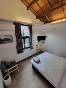 1 dormitorio con 1 cama, 1 silla y TV en OLD WOW老屋瓦共享民宿Hostel 桃園市民宿074號 en Longtan