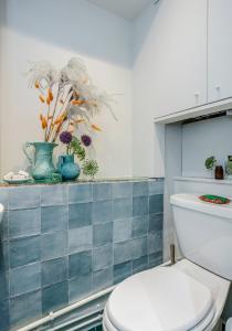 ロンドンにあるNotting Hill London - Chic Bright Apartment W11のバスルーム(トイレ付)が備わります。棚に花を飾っています。