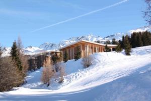 
a snow covered ski slope with a building at L'Aiguille Grive Chalets Hotel in Arc 1800
