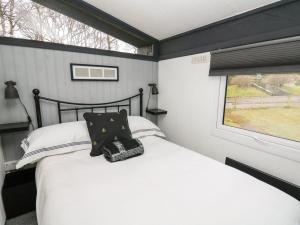 a bedroom with a white bed with a window at 64 Penlan Holiday Park in Newcastle Emlyn