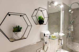 ein Badezimmer mit zwei Spiegeln und zwei Pflanzen an der Wand in der Unterkunft Prime Apartments City Center in Suceava