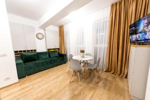 ein Wohnzimmer mit einem grünen Sofa und einem Tisch in der Unterkunft Prime Apartments City Center in Suceava