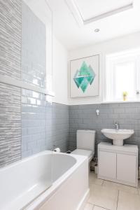 a white bathroom with a tub and a sink at Judah Suites by Koya Homes - TV Bed Apartment, Central High Street, Free Parking in Barry