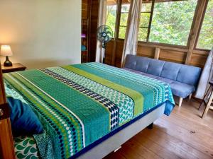 een slaapkamer met een bed, een bank en een raam bij L'Oasis Don Juan in Don Juan