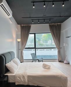 ein Schlafzimmer mit einem Bett und einem Stuhl sowie einem großen Fenster in der Unterkunft Geo Suite - Sunway Pyramid & Sunway Lagoon in Petaling Jaya