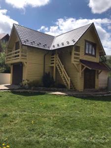 una casa amarilla con porche y patio en Модрина, en Vorokhta