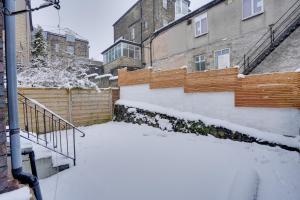 ein schneebedeckter Hof mit einem Zaun und Gebäuden in der Unterkunft Sage Cottage Buxton Family Getaway with Log Fire in Buxton
