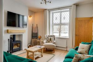 ein Wohnzimmer mit einer grünen Couch und einem Kamin in der Unterkunft Sage Cottage Buxton Family Getaway with Log Fire in Buxton