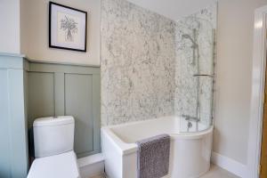 ein Badezimmer mit Badewanne, Toilette und Waschbecken in der Unterkunft Sage Cottage Buxton Family Getaway with Log Fire in Buxton + 35 Fotos