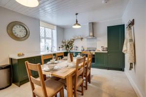 uma cozinha com mesa e cadeiras e um relógio em Sage Cottage: Homely, Cosy Cottage with Log Burner em Buxton