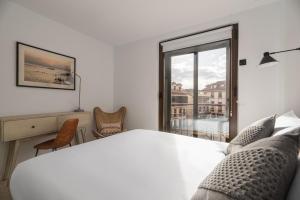 a white bedroom with a large bed and a window at Apartamentos Suite The Way in Astorga