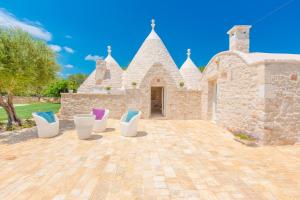 a group of chairs sitting on a patio in front of a building at Trullo Zese con Piscina Privata in San Michele Salentino