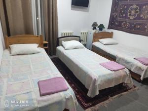2 Betten in einem Zimmer mit lila Handtüchern darauf in der Unterkunft Hotel Mosque Baland in Buxoro