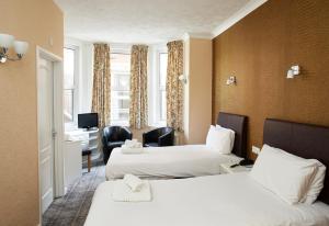Habitación de hotel con 2 camas y escritorio en Palm Court Hotel, en Great Yarmouth