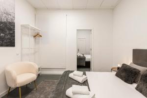 a white bedroom with a bed and a chair at BNBHolder Cheerful La Latina in Madrid