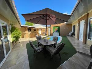 een patio met een tafel en stoelen en een parasol bij AruPar Apartment in Paradera