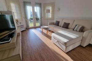 Una sala de estar con un sofá y un televisor de pantalla plana. en OLIVA NOVA, playa, jardín, piscina, golf, MET, IDEAL FAMILIAS, en Oliva