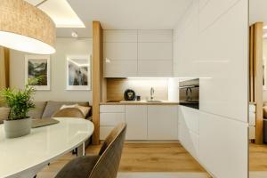 a kitchen with white cabinets and a table and chairs at Apartment Wola, WI-FI, Smart Lock, Air Condition in Warsaw