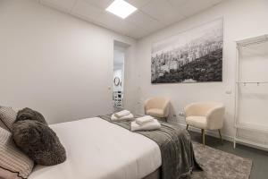 a white bedroom with a bed and two chairs at BNBHolder Cheerful La Latina in Madrid