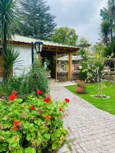 een tuin met rode bloemen en een paviljoen bij Casa de Coria in Chacras de Coria