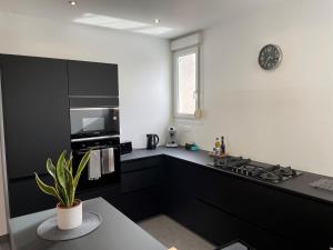 - une cuisine noire et blanche avec une cuisinière et une horloge dans l'établissement Le cinquante-deux appartement de Charme, à Reims