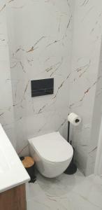 Łazienka z białą toaletą i marmurową ścianą w obiekcie VIP Room 2+2 w Koninie