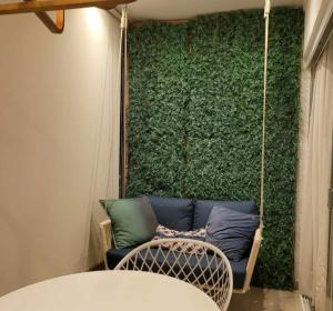 een bank op een schommel voor een groene muur bij Apartamento para temporada mobiliado in Alter do Chao