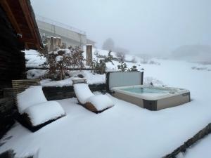 einen schneebedeckten Hof mit einem Whirlpool im Schnee in der Unterkunft Sera Lodge in Grächen