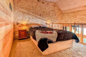 a bedroom with a large bed in a stone wall at Gites de Ponsillou in Lavercantière