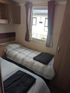 a small room with two beds and a window at Swift holidays at Combe Haven Holiday Park in Hastings