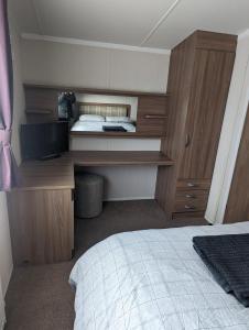 1 dormitorio con 1 cama y escritorio con TV en Swift holidays at Combe Haven Holiday Park en Hastings