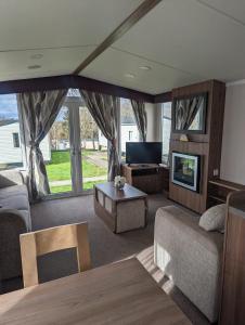 een woonkamer met een bank en een tv bij Swift holidays at Combe Haven Holiday Park in Hastings