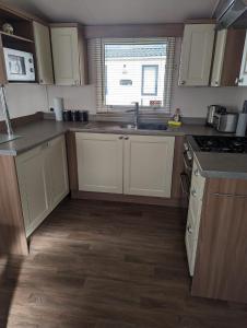 a kitchen with white cabinets and a sink and a window at Swift holidays at Combe Haven Holiday Park in Hastings