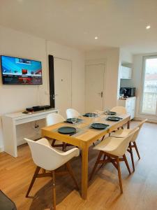 a dining room with a wooden table and white chairs at Lumineux 2 Chambres avec Garage privé - Tram à 1 min in Grenoble