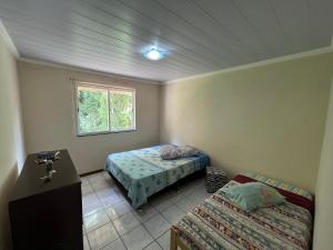 1 dormitorio con 2 camas y ventana en Aconchego em Teresópolis com piscina privativa próximo a feirinha, en Teresópolis