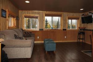 a living room with a couch and some windows at Denali Park View Family Log Cabin in McKinley Park