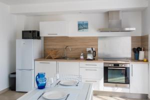 una cocina blanca con una mesa con platos. en Domaine Pedra Llampada Gîte Mer, en Villelongue-dels-Monts