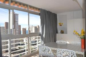 ein Esszimmer mit einem Tisch und Stühlen sowie einem großen Fenster in der Unterkunft Apartamentos Provima in Benidorm