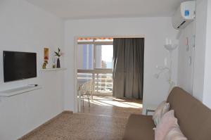 ein Wohnzimmer mit einem Sofa und einem TV in der Unterkunft Apartamentos Provima in Benidorm