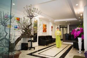 Eine Frau steht in einer Lobby mit Blumen in der Unterkunft My Linh Hotel in Hanoi
