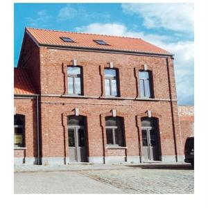 a red brick building with a red roof at De oude statie in Tessenderlo