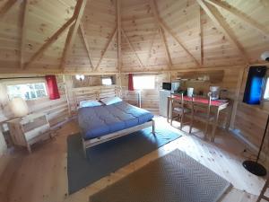 a bedroom in a log cabin with a bed and a desk at Camping le Vallage in Attigny