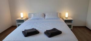 a white bed with two black towels on top of it at Ellas Modern Duplex City Center in Nicosia